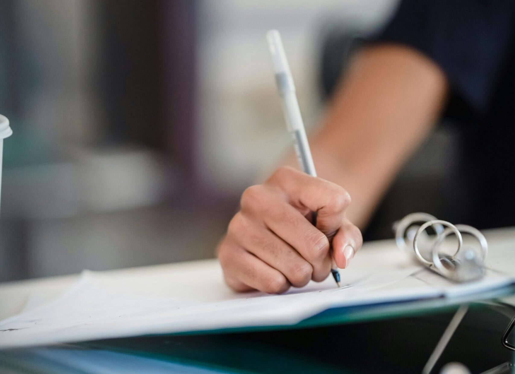 Focused image of a businesswoman writing notes in a professional office setting.